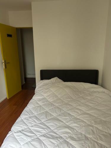 - un lit blanc dans une chambre avec une porte jaune dans l'établissement Agréable Chambre Confortable 2, à Asnières-sur-Seine