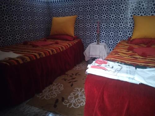 a bedroom with two beds and a table with a lamp at Chez hiba in Rabat