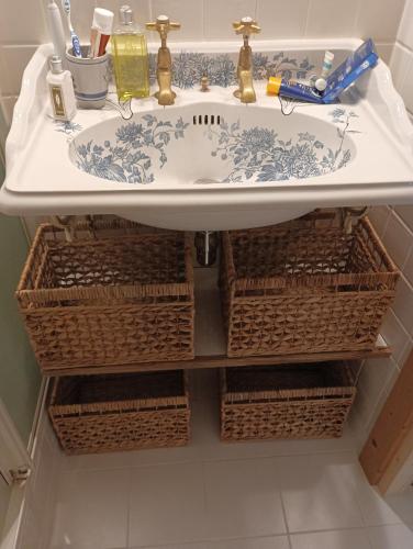 La salle de bains est pourvue d'un lavabo et de paniers. dans l'établissement Chambre d'hôte Les Oulies Bédoin, à Bédoin