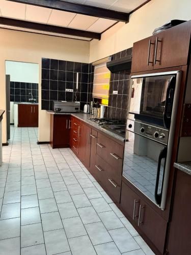 a large kitchen with brown cabinets and a tile floor at Senate Way Guest House in Kimberley