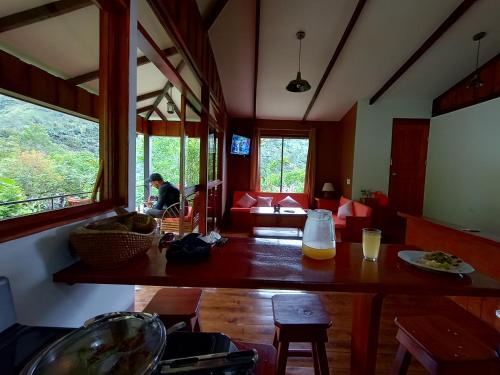 a living room with a table and a person sitting in the window at Aloha chirripo cabaña familiar in Convento