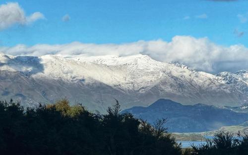 a snow covered mountain with clouds in the background at On the Beach in Hokitika