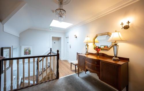 a hallway with a staircase with a dresser and a mirror at Kells Bay House and Gardens in Kells