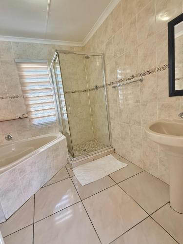 a bathroom with a shower and a tub and a sink at Senate Way Guest House in Kimberley