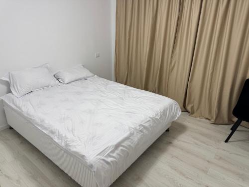 Una cama con sábanas blancas y almohadas en un dormitorio. en Central Apartments, en Craiova