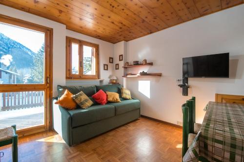a living room with a green couch and a television at Chez Umbus, centrale e immerso nel verde, grande terrazzo in Champoluc