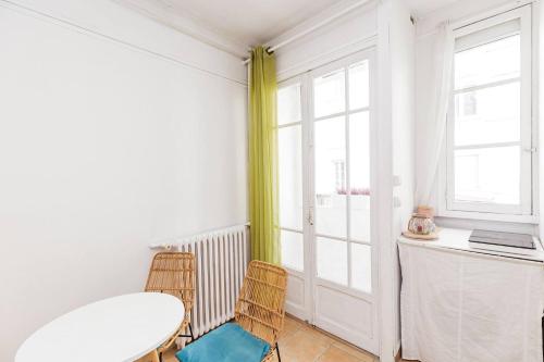 a room with a table and two chairs and a desk at L'Écrin - Studio Calme - Proche Bois de Vincennes & Métro in Vincennes