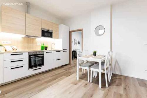 a kitchen with white cabinets and a table and chairs at Angel in Brno