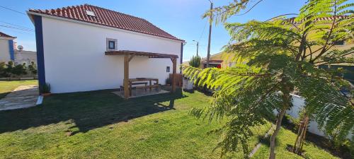 a small white building with a bench in the yard at B House in Cabeço da Moucheira