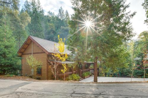 a log cabin in the woods with the sun shining at Bear Lodge Waterfront Cabin with Level 2 EV Charger in Sutter Creek