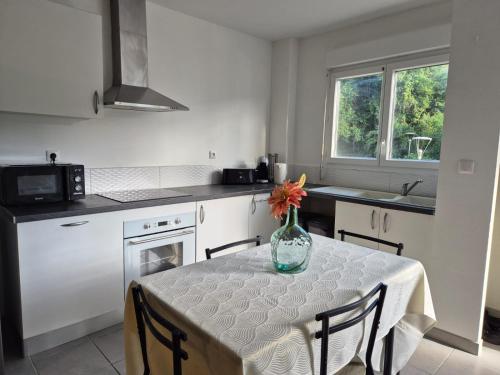 a kitchen with a table with a vase of flowers on it at Foyal Toloman - Flanboyan lodge in Les Trois-Îlets