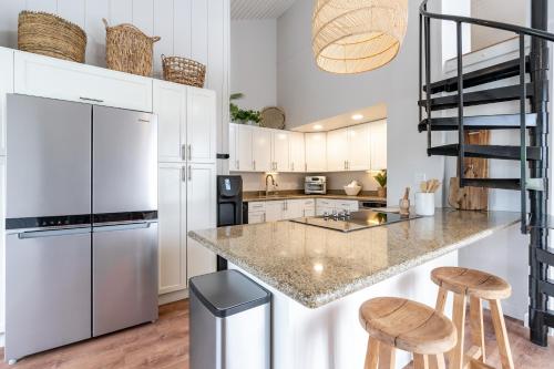 a kitchen with white cabinets and a counter with stools at The Drifter - North Shore Loft - Relaxed Luxury in Kahuku