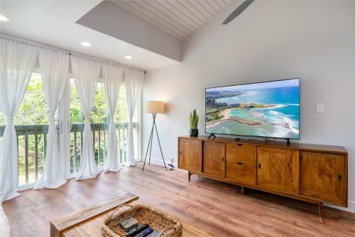 a living room with a flat screen tv on a wooden dresser at The Drifter - North Shore Loft - Relaxed Luxury in Kahuku