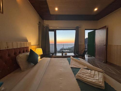 a bedroom with a large bed with a large window at Vansathli I Near Mall Road Kasauli I Open Garden & Rooftop I by Humble stay villa in Kasauli