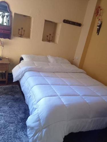 a large white bed sitting in a bedroom at Hostal Santa Isabel in Iza