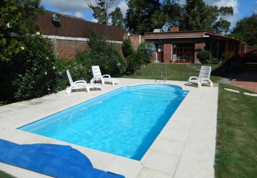 a swimming pool with two chairs and a group at Chalet ALTOS DEL PINAR in Punta del Este