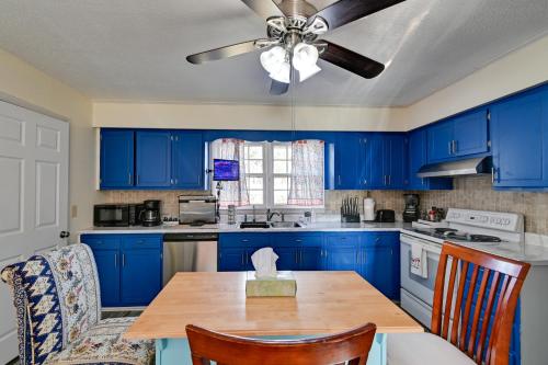 a kitchen with blue cabinets and a table with a ceiling fan at Near Fort Liberty Home with Yard in Fayetteville! in Fayetteville