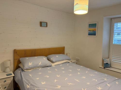 een slaapkamer met een bed met witte lakens en kussens bij Newlyn Harbour Cottage in Newlyn