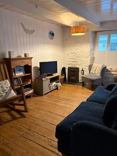 een woonkamer met een bank en een tv bij Newlyn Harbour Cottage in Newlyn
