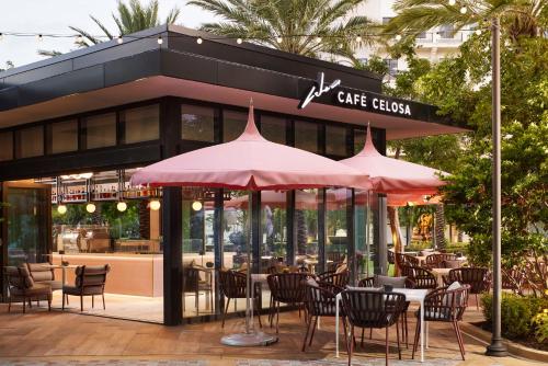 a cafe with tables and chairs and umbrellas at Loews Coral Gables Hotel in Miami