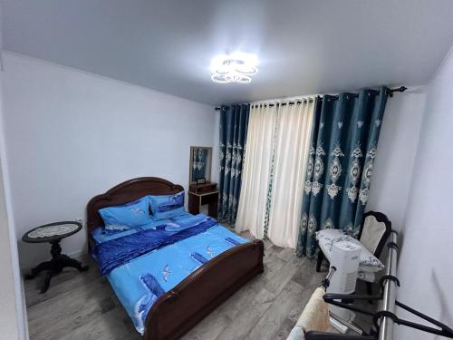 a bedroom with a bed with a blue comforter at Милый дом in Tokmok