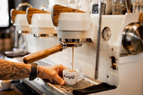 a person is preparing a cup of coffee in a espresso machine at Ace Hotel & Swim Club Athens in Athens
