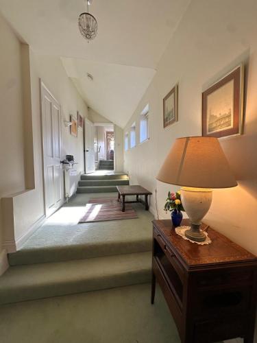 a hallway with a lamp on a table and stairs at 30 Park Street in Hungerford