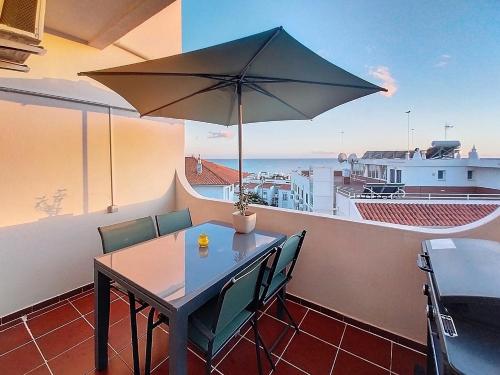 a table and chairs with an umbrella on a balcony at Silmaria Sea View amazing in Albufeira