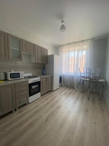 a kitchen with white appliances and a table with chairs at Комфортабельные - уютные апартаменты в Костанай Береке 63 in Kostanay