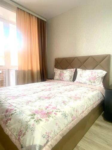 a bedroom with a large bed with pink flowers at Комфортабельные - уютные апартаменты в Костанай Береке 63 in Kostanay
