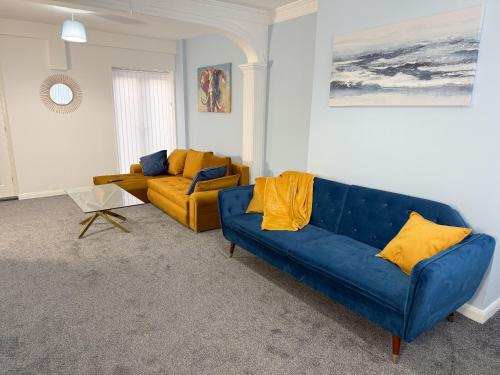 a living room with a blue couch and yellow pillows at Millbrook Blues 2BR Entire Home in Middlesbrough