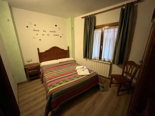 a bedroom with a bed and a chair and a window at Hostal La Balsá in La Alberca