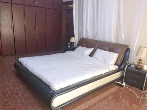 a bed with white sheets and a leather headboard in a bedroom at Akright Villa in Buzzi