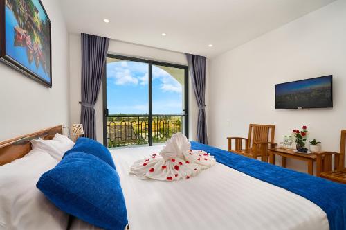 a bedroom with a large bed with a large window at Hoi An Legend Charm Boutique Hoi An Hotel in Hoi An