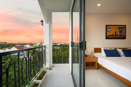 a bedroom with a bed and a balcony at Hoi An Legend Charm Boutique Hoi An Hotel in Hoi An