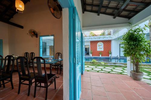 a dining room with a table and chairs on a patio at Hoi An Legend Charm Boutique Hoi An Hotel in Hoi An