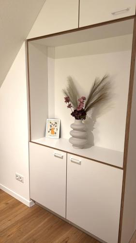 a white cabinet with a vase with flowers in it at K14 FeWo - Am Kurpark - Therme in Bad Saarow