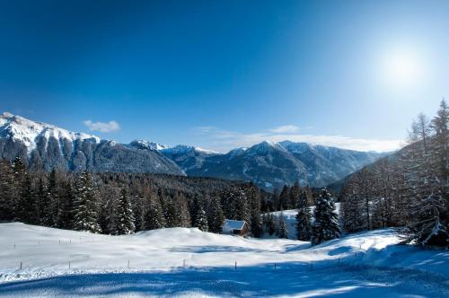 a snow covered mountain with a house in the distance at Garnì Aurora Bed and Breakfast in Soraga