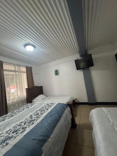 a bedroom with two beds and a ceiling at Hotel Tabacones Guacimo in Guácimo