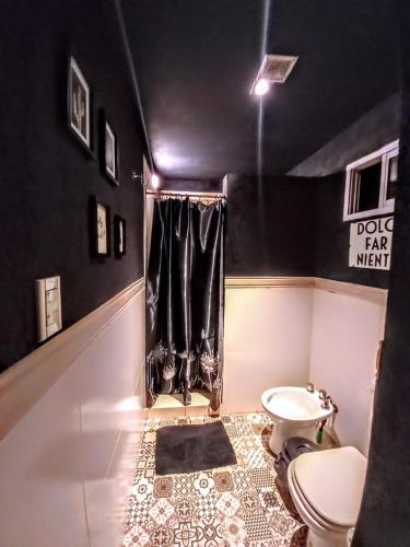 a bathroom with a toilet and a black wall at Puesto Potrillos in Villa Yacanto