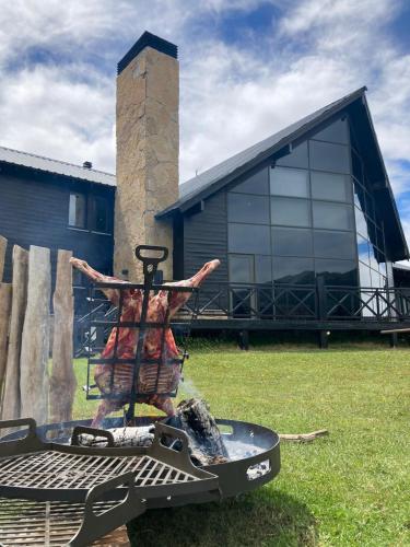 a grill in a field with a building in the background at AMANCIO Hotel & Cabañas in Villa Meliquina