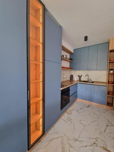 a kitchen with blue cabinets and a marble floor at Yves Lake Front Apartments in Ohrid