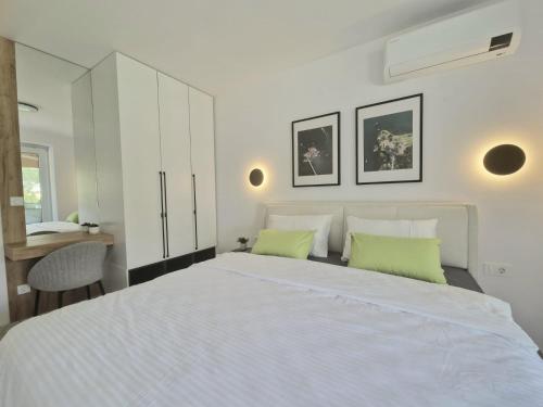 a bedroom with a large white bed with two green pillows at Yves Lake Front Apartments in Ohrid