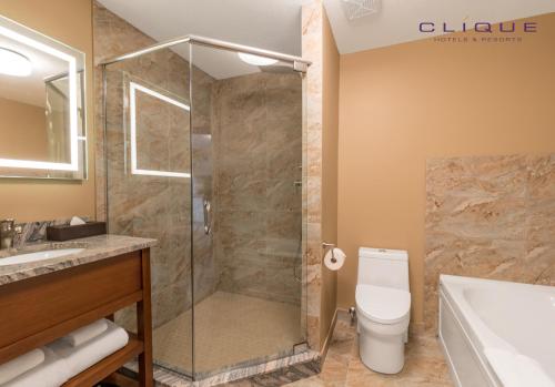 a bathroom with a shower and a toilet and a sink at Falcon Crest Lodge by CLIQUE in Canmore
