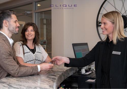 a man and woman shaking hands at a counter at Falcon Crest Lodge by CLIQUE in Canmore