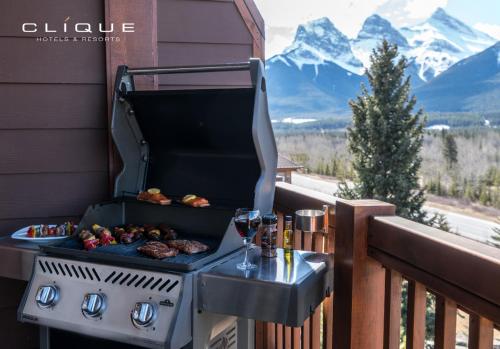 a grill on a balcony with wine glasses and food at Falcon Crest Lodge by CLIQUE in Canmore