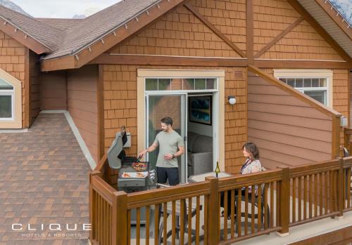 a man and a woman standing on a porch of a house at Falcon Crest Lodge by CLIQUE in Canmore