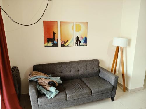 a couch in a living room with three paintings at Departamento Torre Cabildo in San Salvador de Jujuy