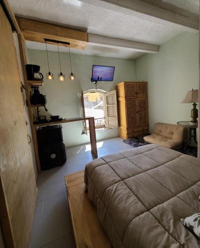 a bedroom with a bed and a couch and a television at Casa Tatewari in San Luis Potosí