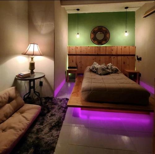 - une chambre avec un lit et un canapé avec des lumières violettes dans l'établissement Casa Tatewari, à San Luis Potosí